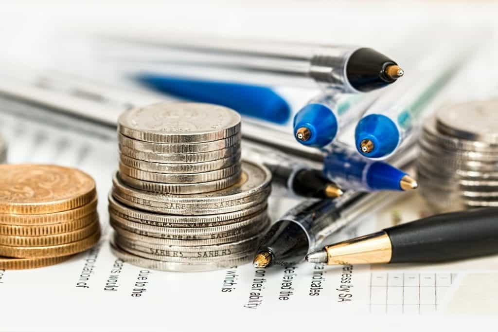 A stack of coins next to a stack of pens.