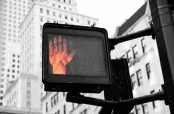 A traffic crossing illuminates a red hand to indicate stopping.