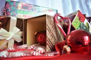 Overflowing gold gift boxes, candy canes, and red ornaments piled together on a red blanket.