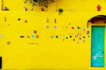 A highly decorated bright yellow wall and blue-green door in Salta, Argentina.