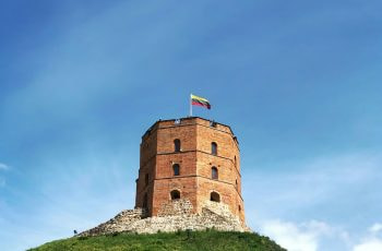 A tall brick tower on top of a grassy hill.